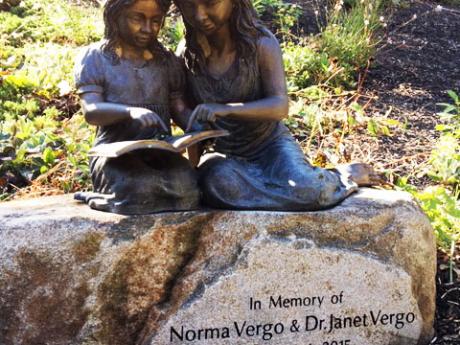 Statue of two girls perched on a rock and reading a book.