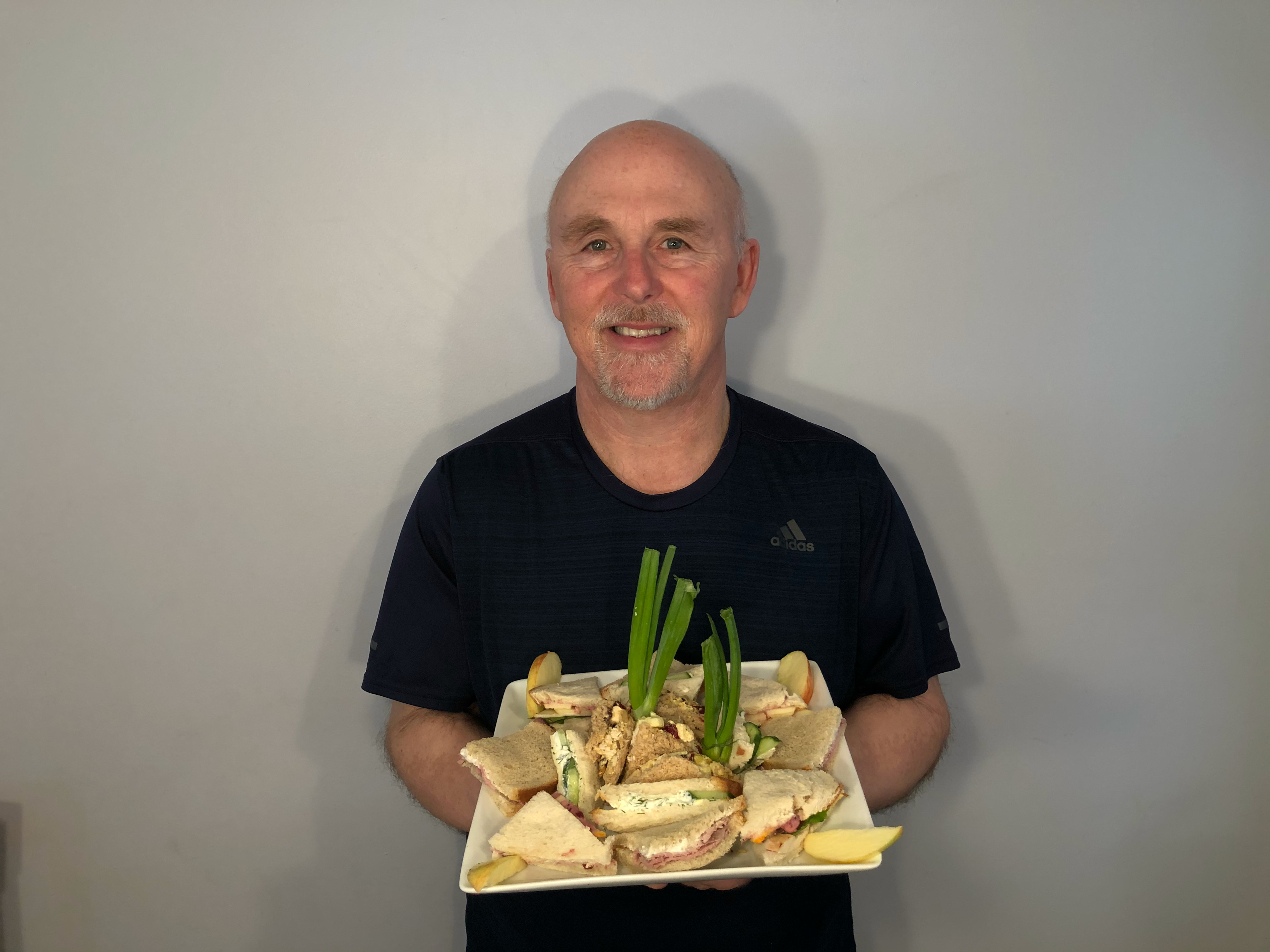 Photo of Chef Rob holding a plate of tea sandwiches.
