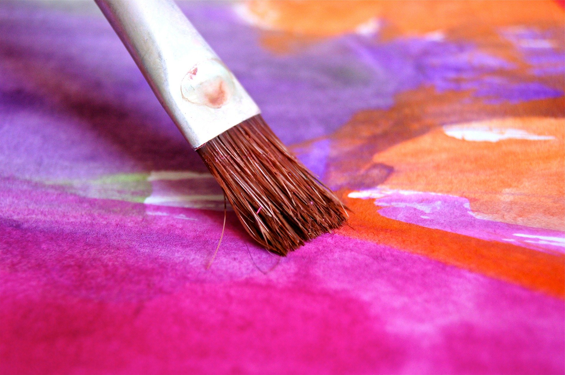 Photo of a paint brush applying watercolor to paper.