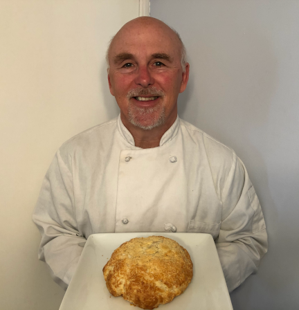 Photo of Chef Rob holding a plate of Asiago Cheese Bread.