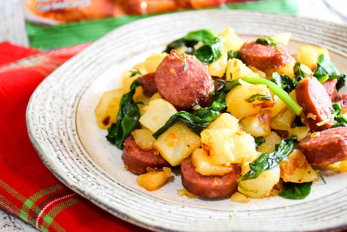 Photo of a plate of red potatoes, kielbasa and spinach.