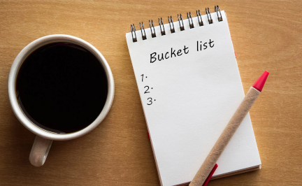 Photo of a pad with Bucket List written at the top, a pen and a mug of coffee.