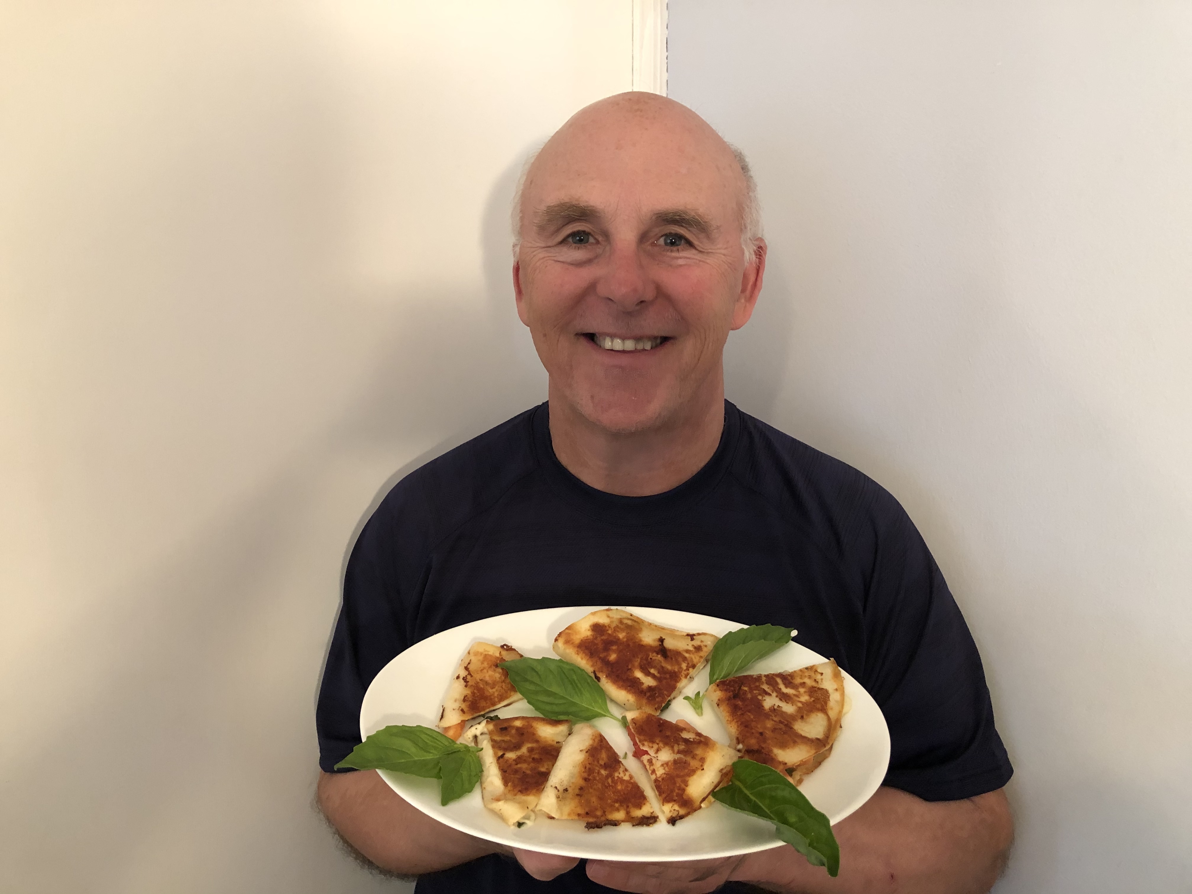 Photo of Chef Rob holding a plate of mozzarella, tomato and basil quesadillas.