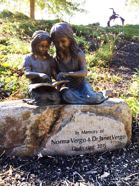 Statue of two girls perched on a rock and reading a book.