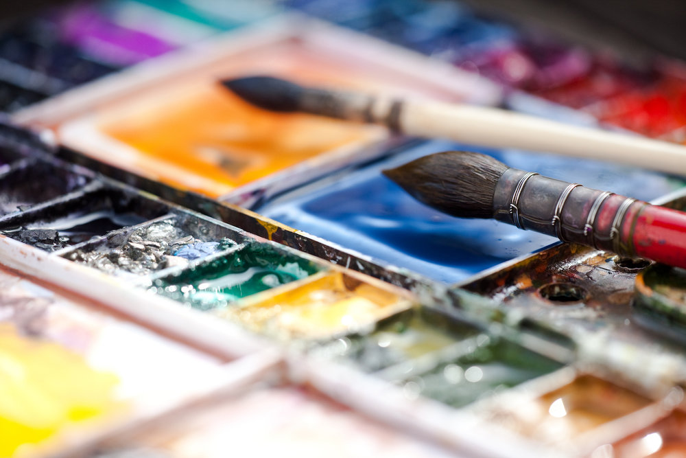 Photo of a paint brush and a watercolor paint palette.