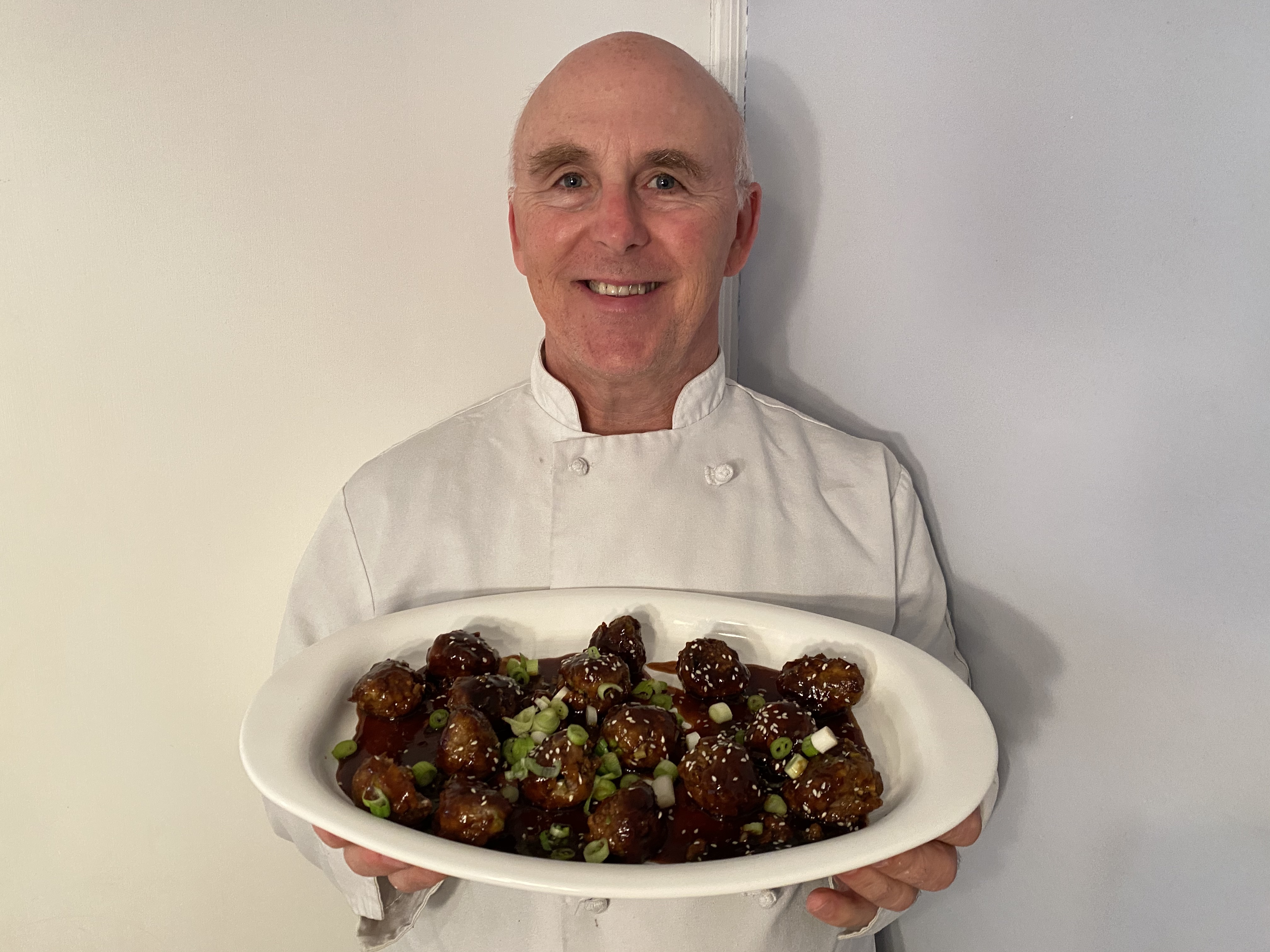 Chef Rob holding a plate of Generals Tso's Meatballs.