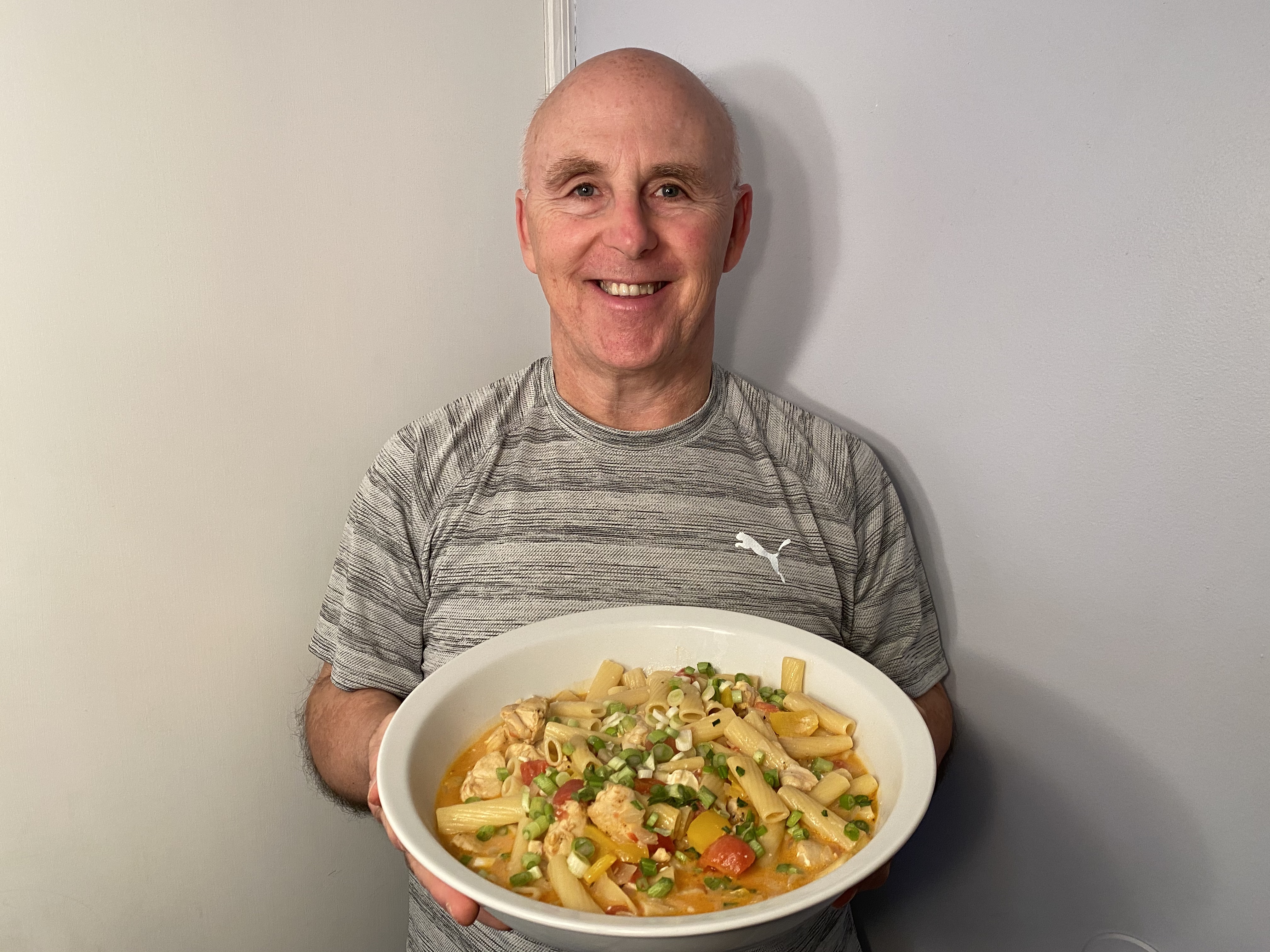 A photo of Chef Rob holding a plate of Cajun Chicken Penne.