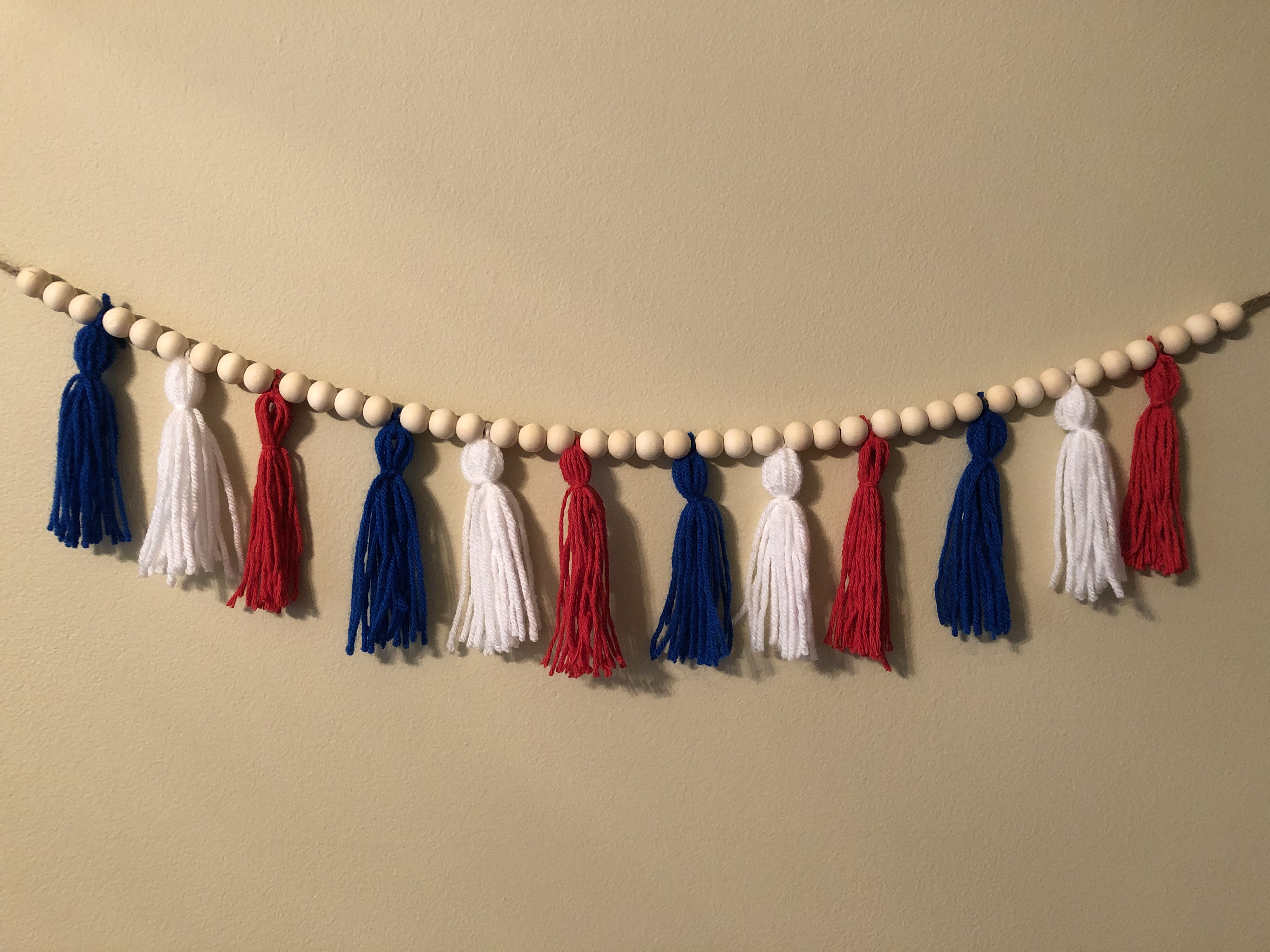 Photo of a wooden bead garland decorated with red, white and blue tassels.
