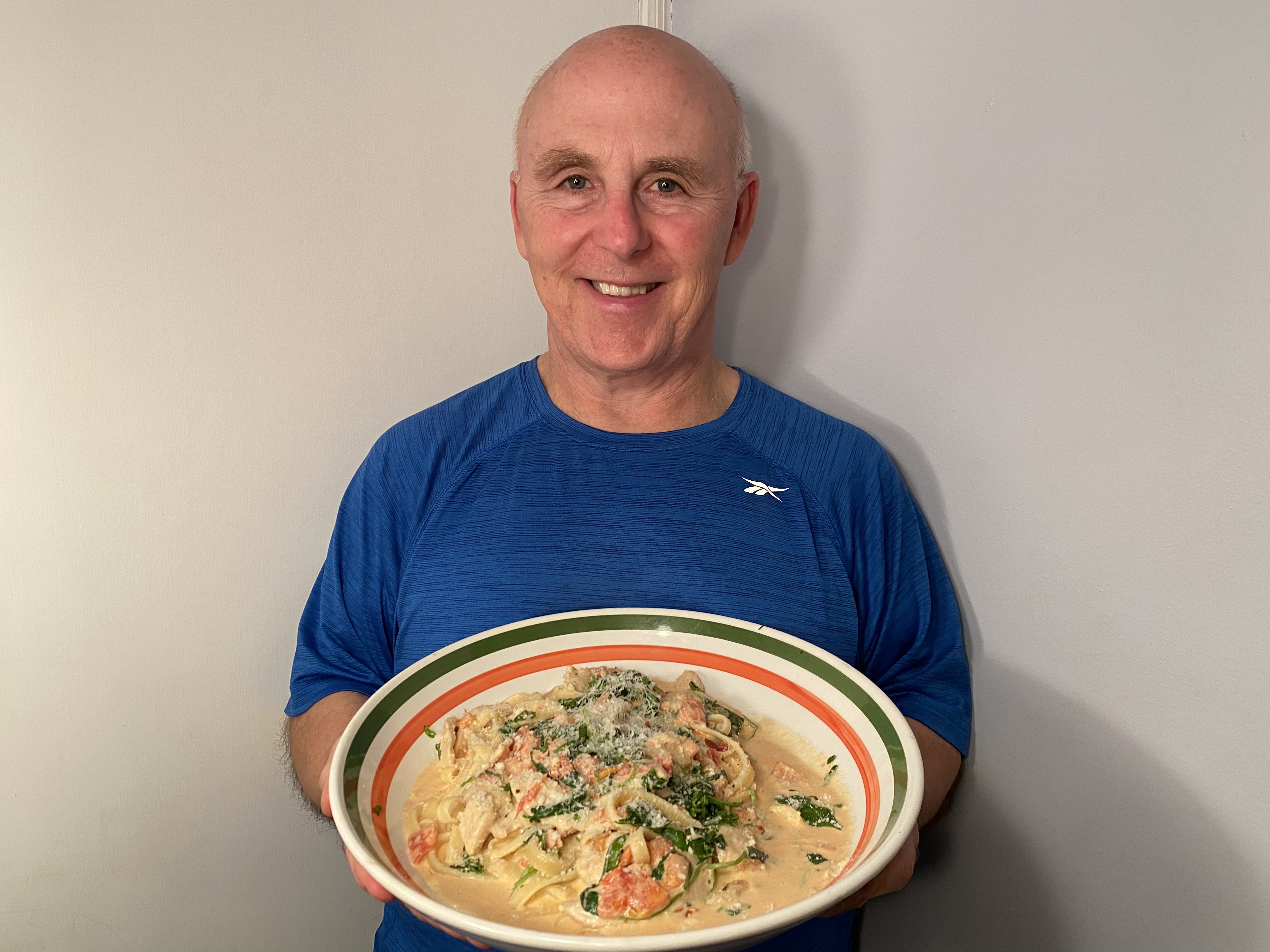 Photo of Chef Rob holding a bowl of Tuscan Chicken with Fettucine.