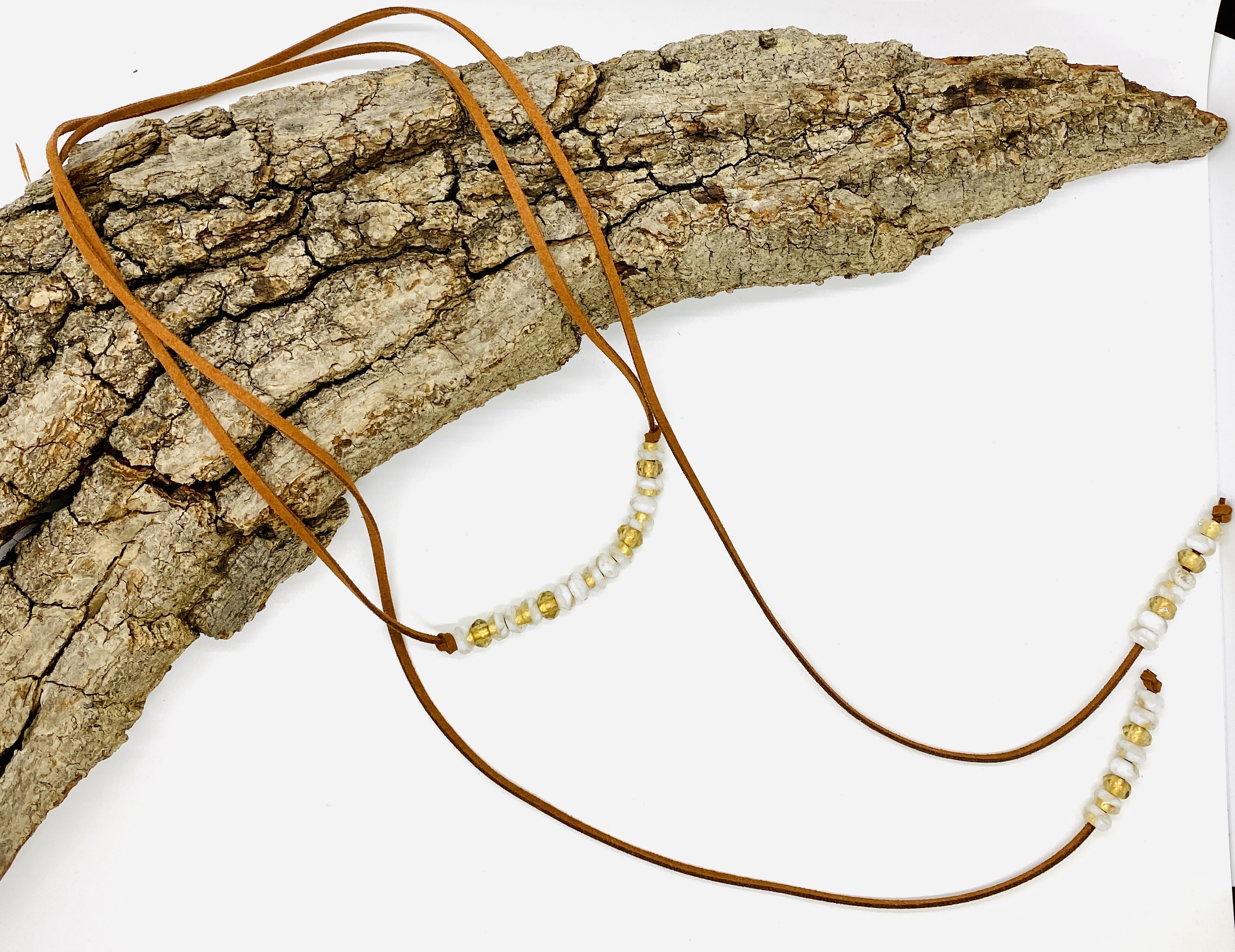 A photo of a Boho wrap necklace draped over a piece of driftwood.