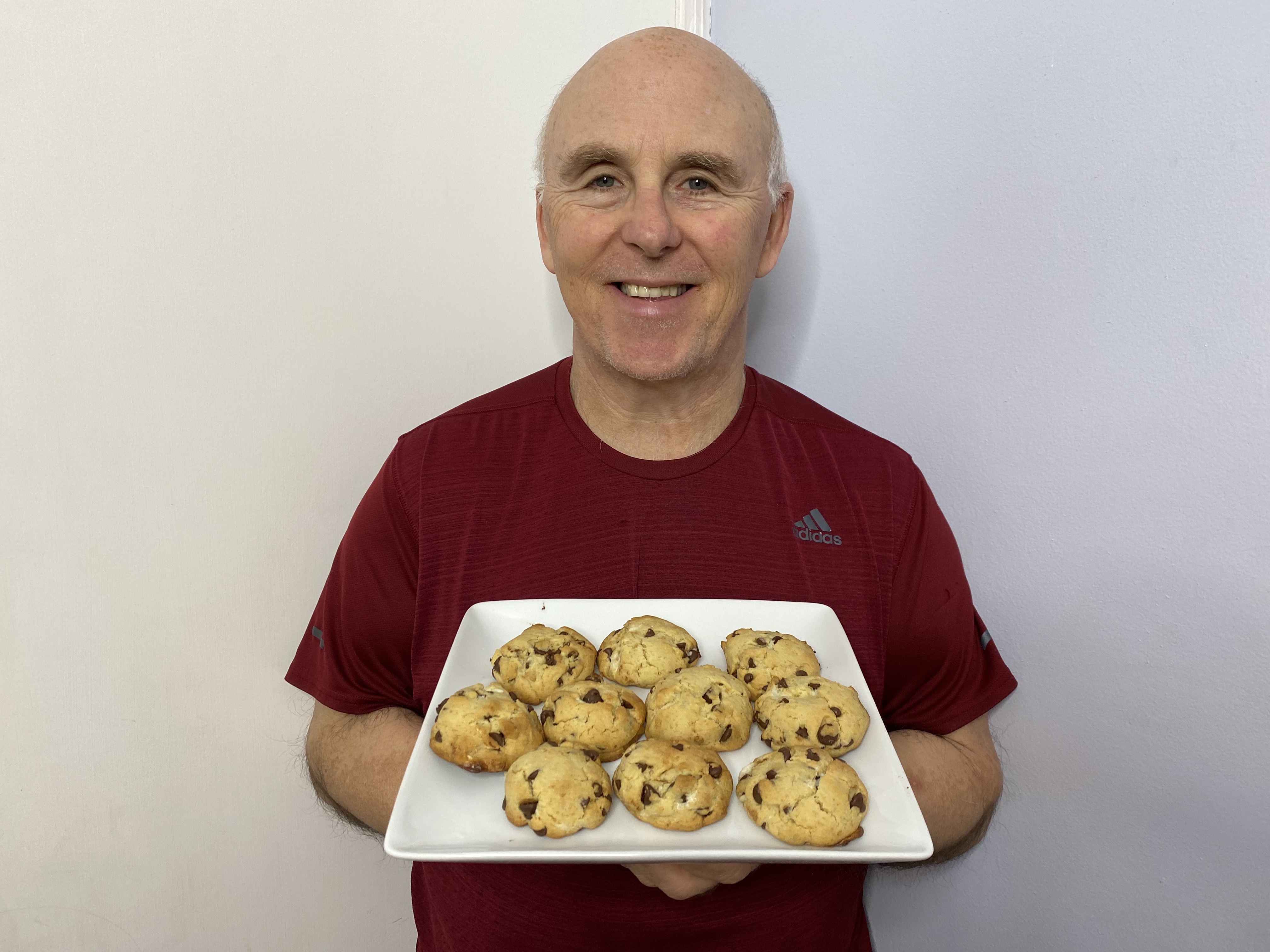 A photo of Chef Rob holding a plate of Cheesecake Stuffed Chocolate Chip Cookies.