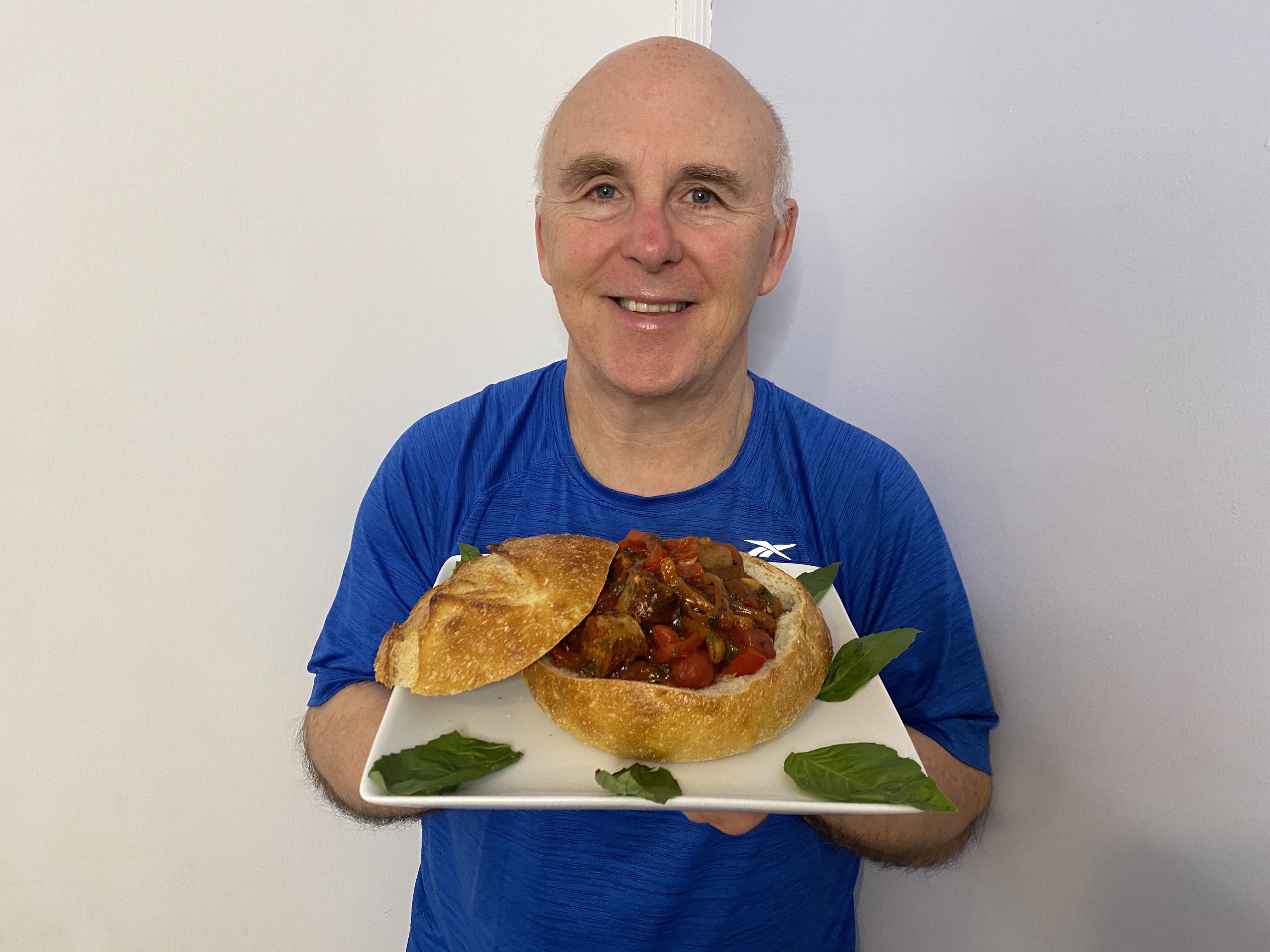 Chef Rob holding a plate containing Sausage, Peppers and Onions in a Bread Bowl.