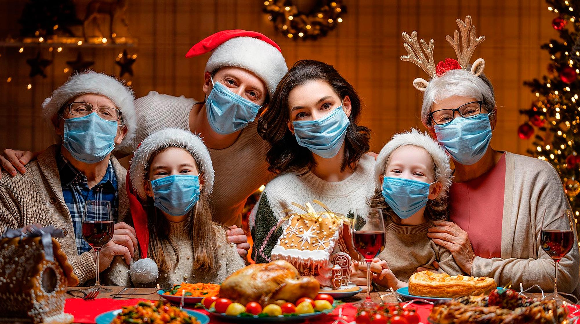 Photo of a multi-generational family wearing Santa hats and surgical masks.
