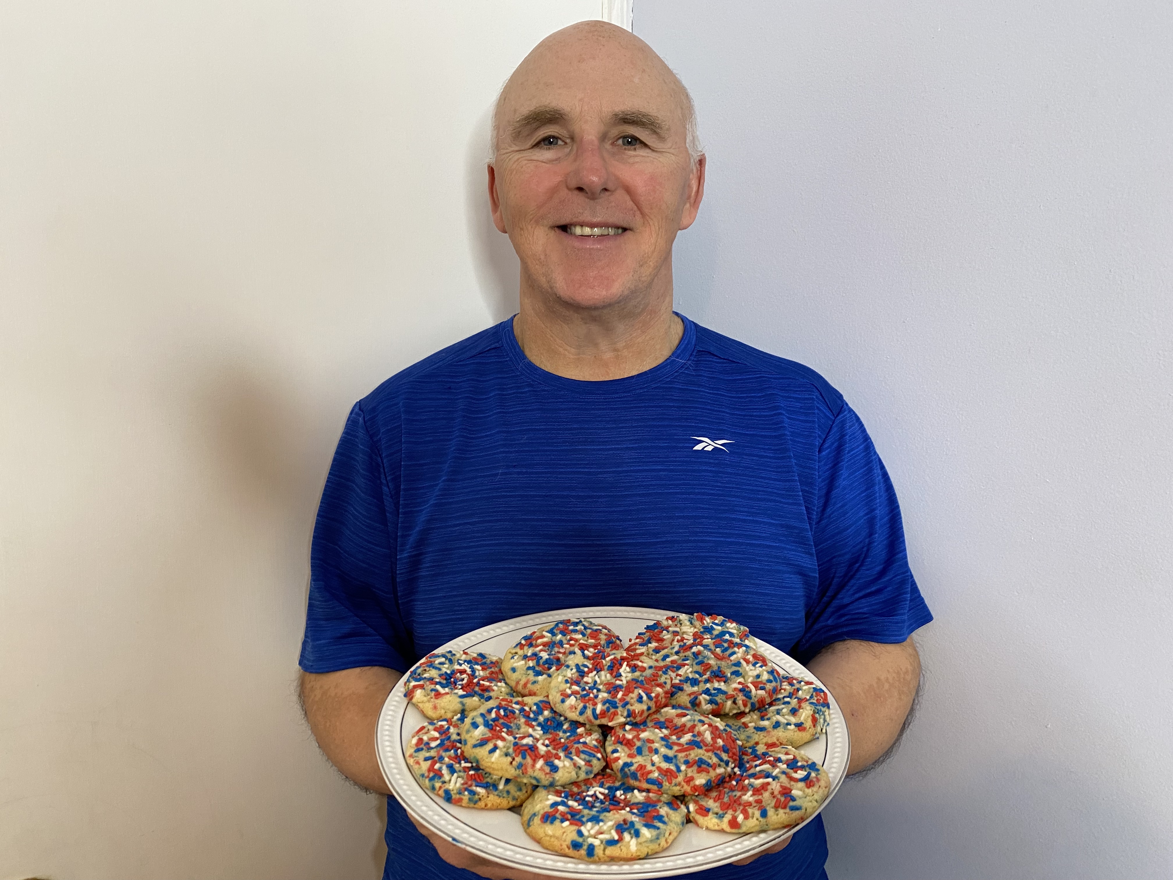 A photo of Chef Rob holding a plate of butter cookies with red, white and blue sprinkles on top.