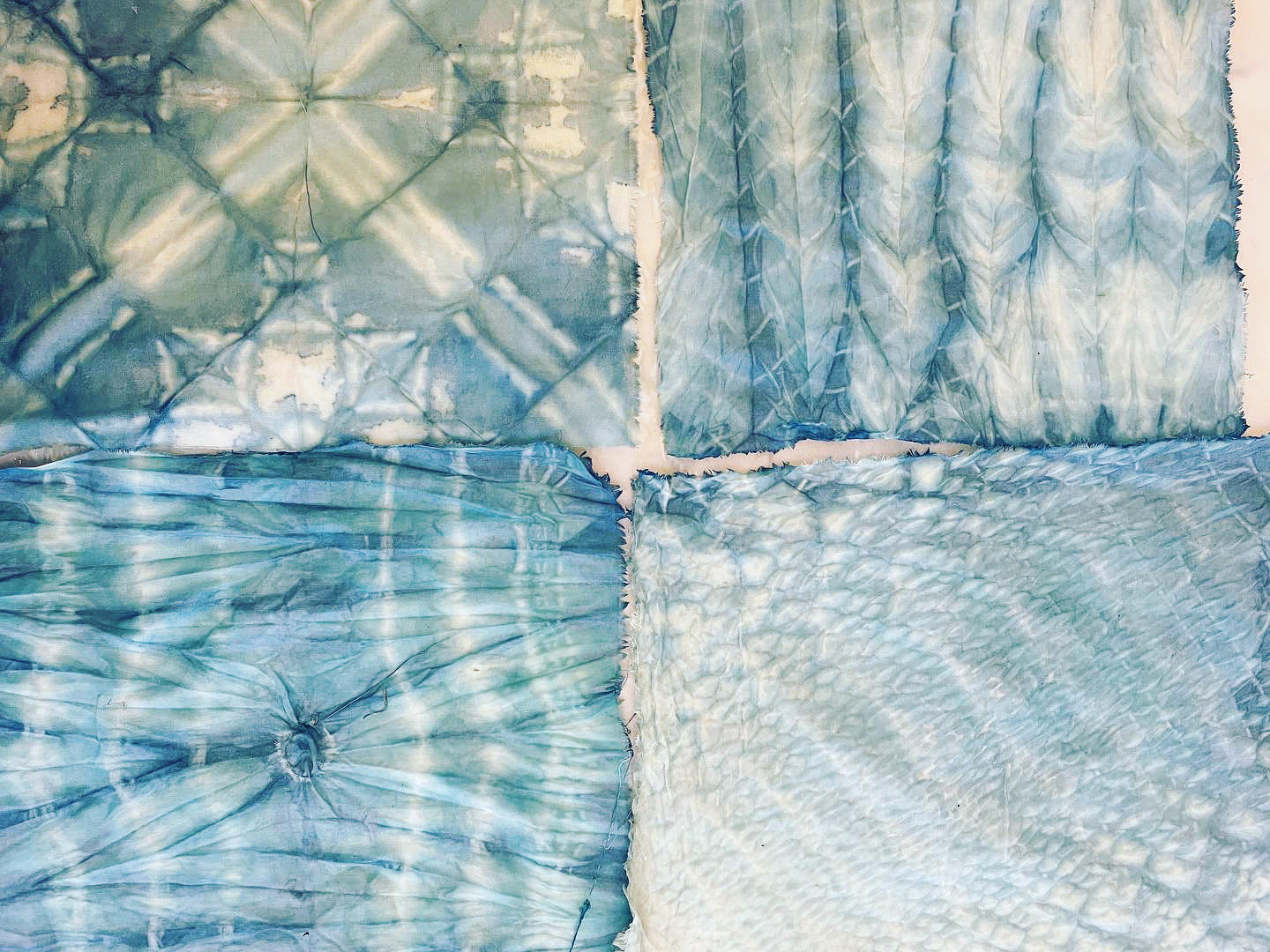 A photo of four pieces of fabric dyed using the shibori technique.