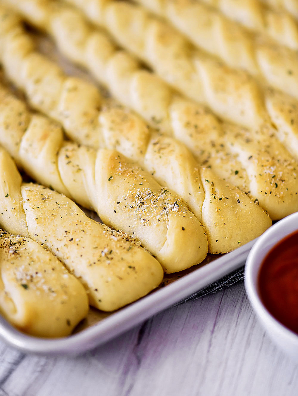 A color photo of bread sticks lined up on a baking sheet.
