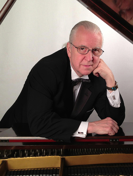 A color photo of pianist Stan Wiest leaning his elbow on a piano.