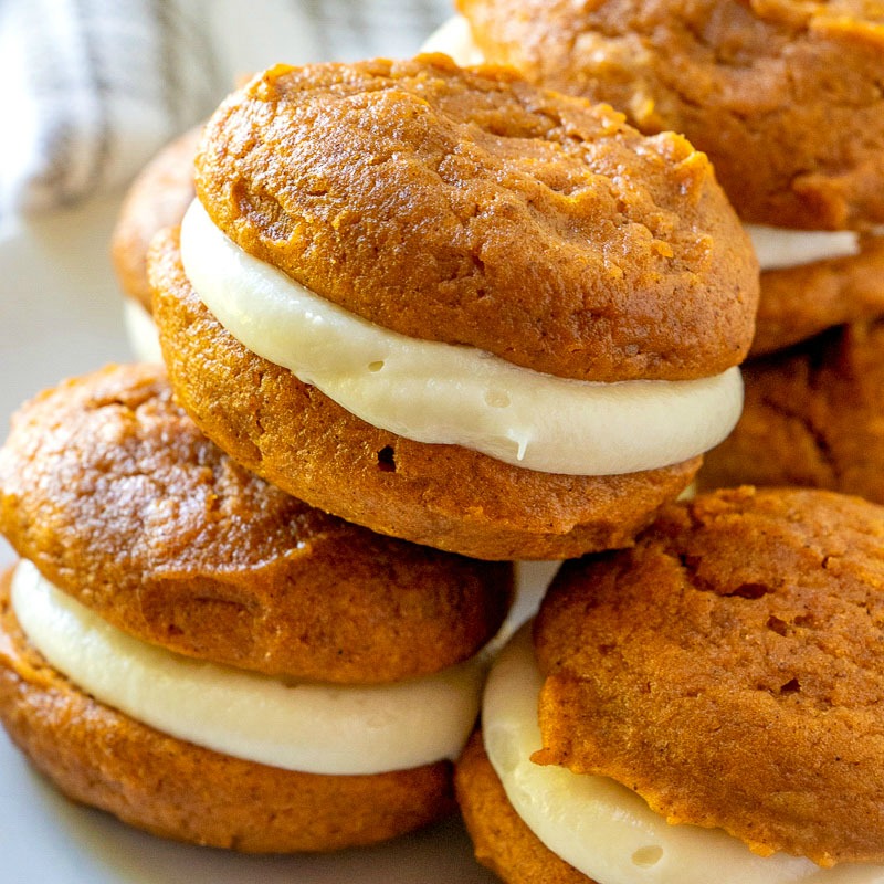 A color photo of pumpkin whoopie pies on a plate.