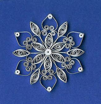 Image of a snowflake on a blue background. The snowflake is made with a technique known as quilling, or coiling, strips of paper to make a design.