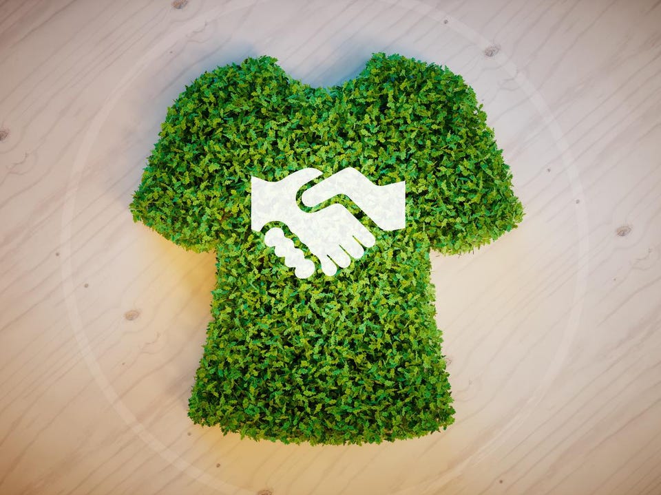 A graphic featuring a shirt made from leaves with the image of two hands shaking on the front.