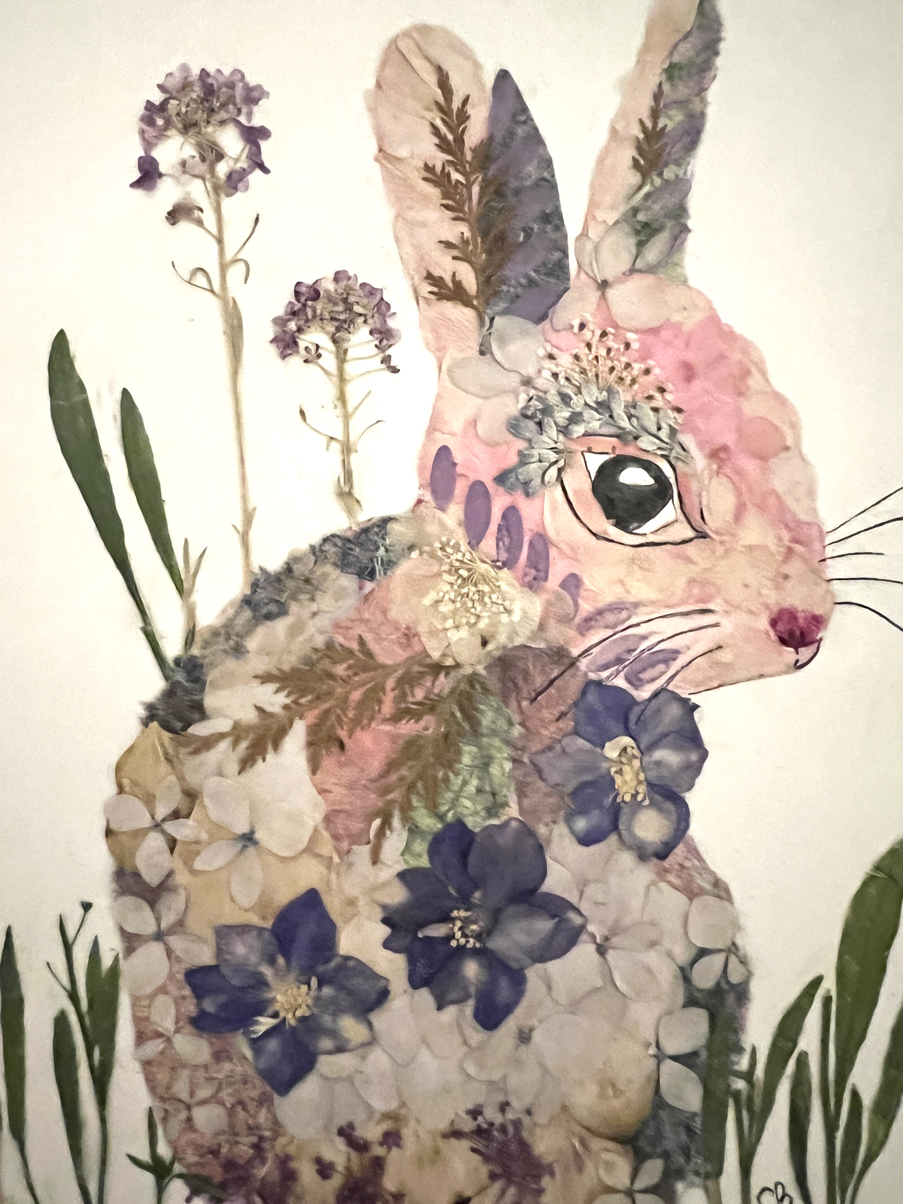 A photo of a bunny made using pink and purple dried flowers.