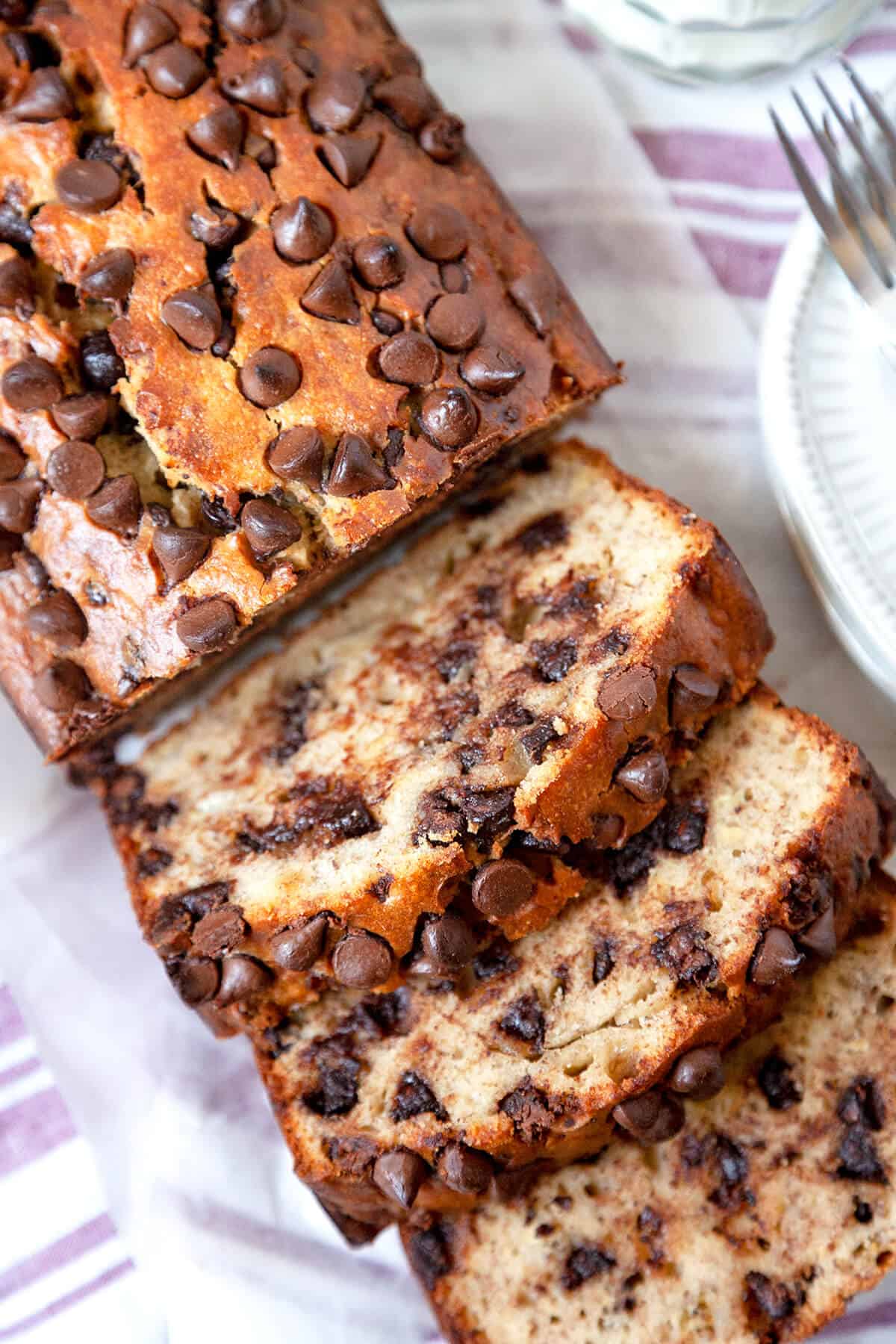 A color photo of a partially sliced loaf of chocolate chip banana bread.