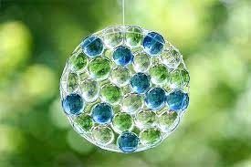 A photo of a round suncatcher made with blue and green glass beads.