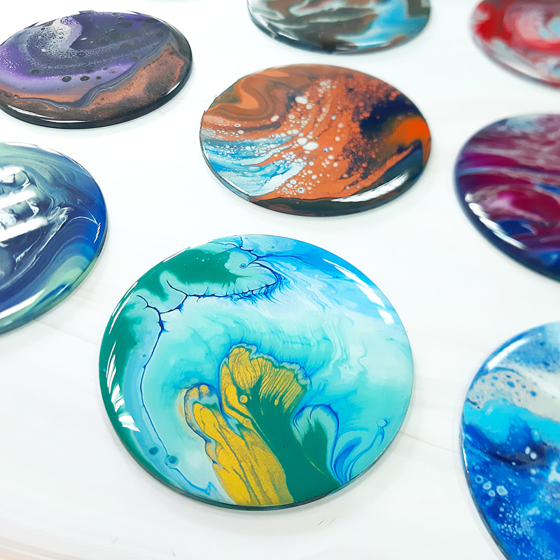 A photo of round coasters created using the technique of pour painting.