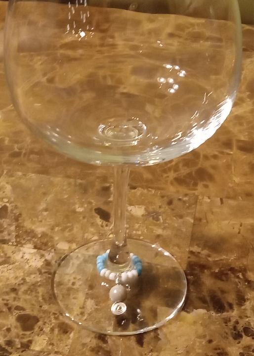 A color photo of a wine charm around the stem of a wine glass.
