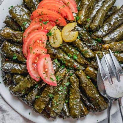 A color photo of a plate of stuffed grape leaves.