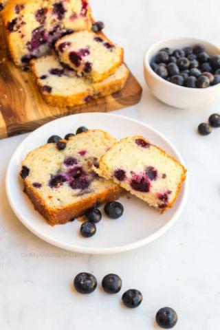 A photo of a slice of blueberry bread on a plate.