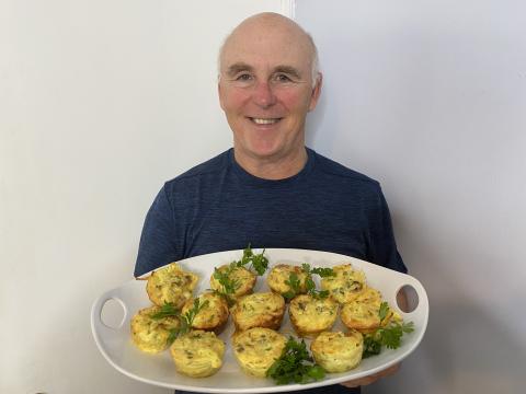 A Photo of Chef Rob holding a plate of mini Asiago, Pasta and Prosciutto Frittatas.