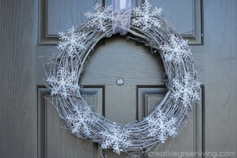 A photo of a wreath made from grapevines and adorned with white snowflakes.