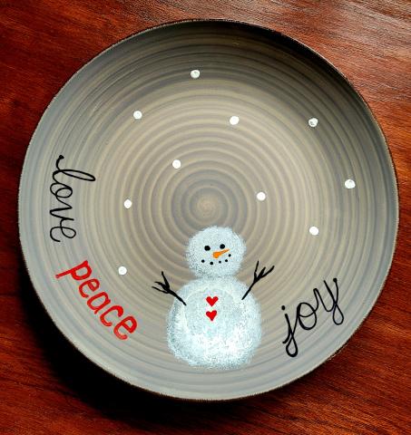 A photo of a plate painted with a snowman and the words love, peace, joy.