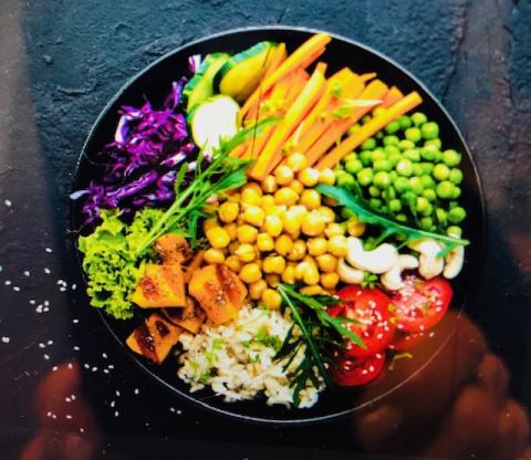 A color photo of a bowl filled with colorful vegetables and legumes.