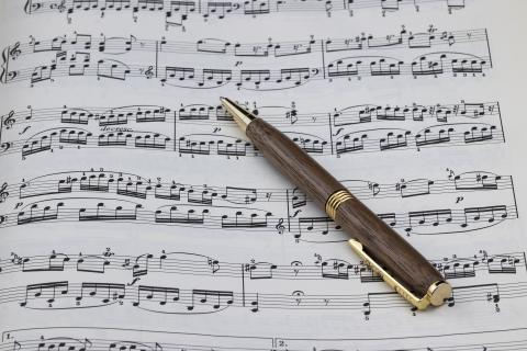 A photo of a pen sitting atop sheet music.