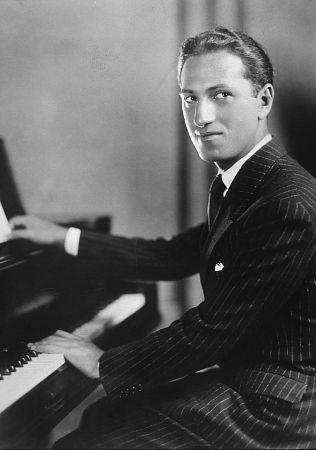 A black and white photo of George Gershwin seated at the piano.