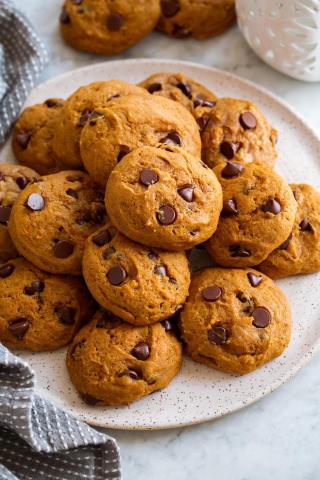 A color photo of a plate of pumpkin chocolate chip cookies.