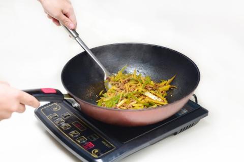 A color photo of food being stir-fried in a wok.