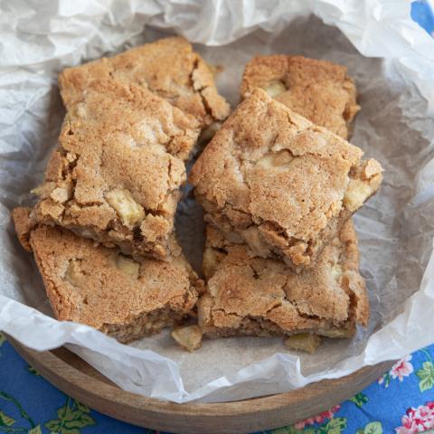 A color photo of apple brownies in a wooden bowl.