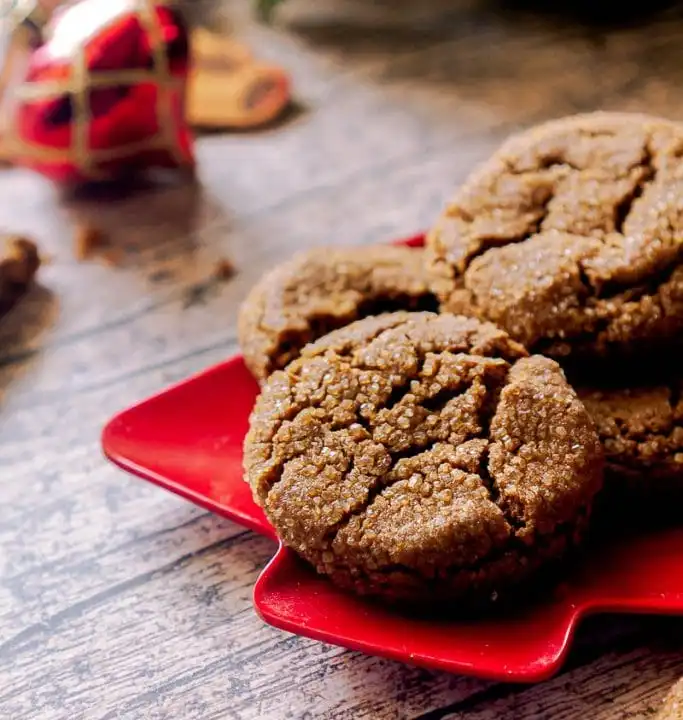 A color photo of round gingersnap cookies on a red plate.