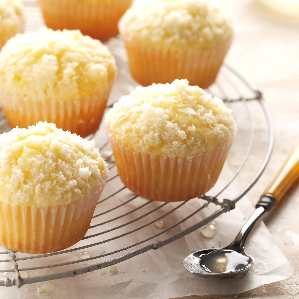 A color phot of several lemon crumb muffins in paper liners on a round baking rack.