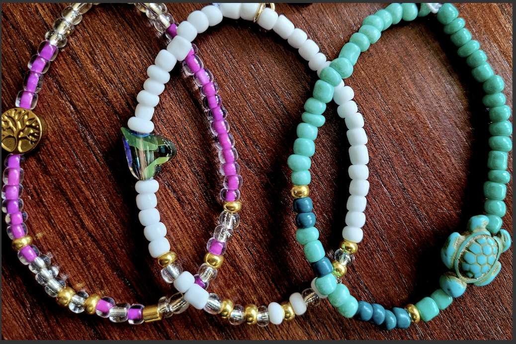 A color photo of three morse code beaded bracelets on a wooden surface.