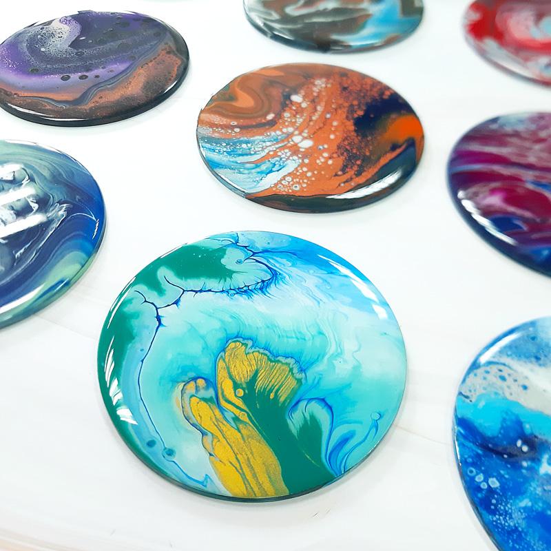 A photo of round coasters created using the technique of pour painting.