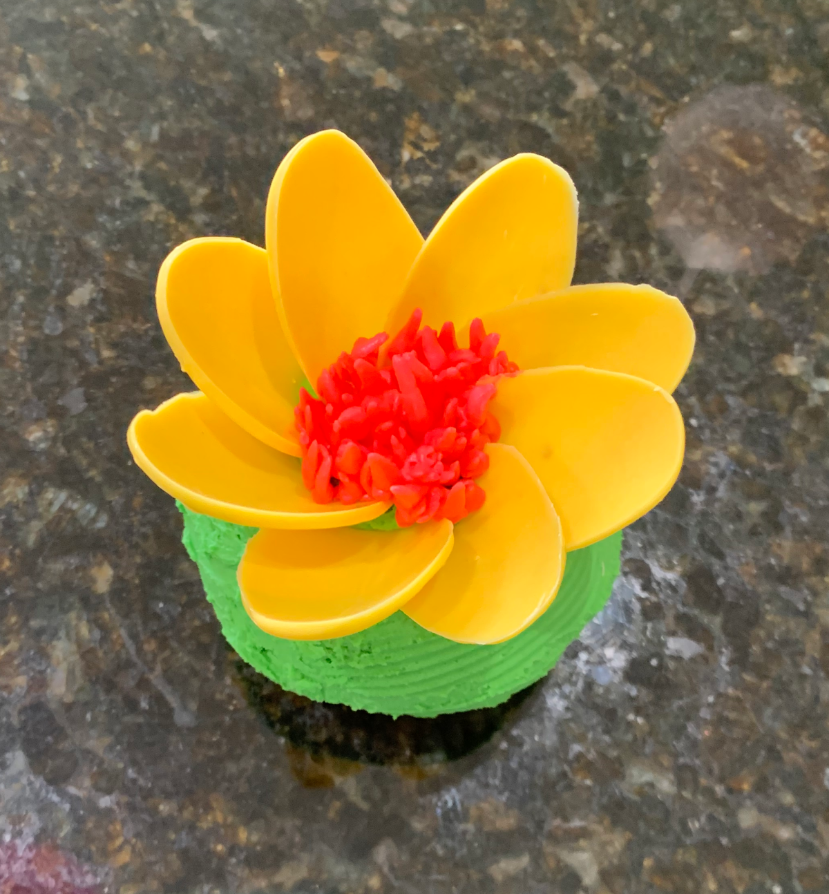A photo of a cupcake decorated with a yellow flower.
