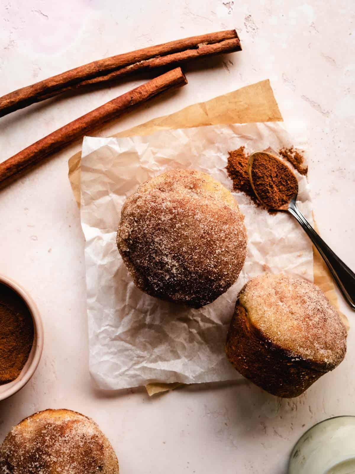 A photo of cinnamon dusted muffins on parchment paper.