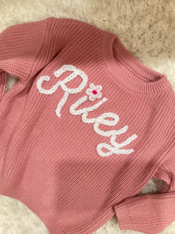 A sweater adorned with the name Riley in chunky embroidery.